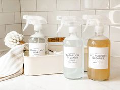 three bottles of bathroom cleaner sitting on a counter top next to a basket filled with towels