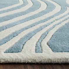 a blue and white rug with wavy lines on the floor in front of a wooden floor