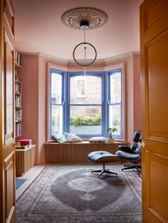 an empty room with a chair, bookshelf and window