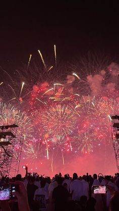 fireworks are lit up in the night sky and people are taking pictures with their cell phones