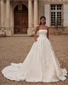 a woman standing in front of a building wearing a wedding dress