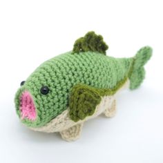 a crocheted green fish with pink nose and mouth sitting on a white surface