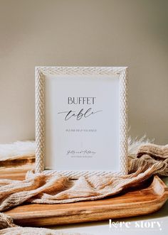 the buffet table sign is placed on top of a cutting board with a blanket around it