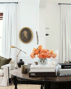 a living room filled with lots of furniture and flowers on top of each table in front of a window