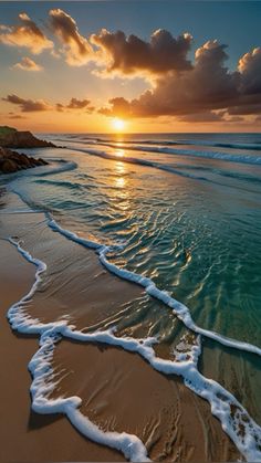 the sun is setting over the ocean with waves coming in to shore and some rocks on the beach