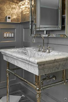 a bathroom with a marble sink and large mirror on the wall above it is decorated in gold