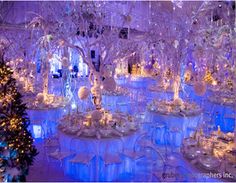 the tables are decorated with white flowers and crystal trees for an elegant wedding reception at night