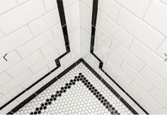 the corner of a tiled bathroom with black and white tiles on the walls, floor and ceiling