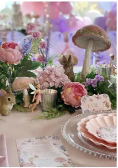 a table topped with lots of pink flowers and bunny figurines on top of it