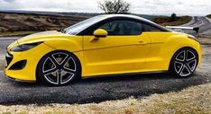 the yellow sports car is parked on the side of the road in front of some hills