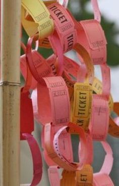 a bunch of pink and yellow ribbons hanging from a pole