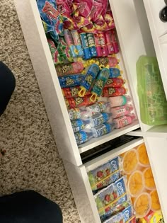 an open pantry filled with lots of food and drinks next to a person's feet