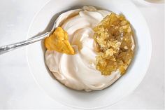 a white bowl filled with cream and toppings on top of a table next to a spoon