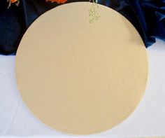 a white table topped with a wooden plate covered in flowers and blue satin fabric behind it