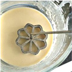 a glass bowl filled with liquid and a metal spoon