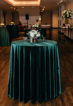 a green table cloth with white flowers on it and people sitting at tables in the background