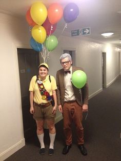 two people standing in an office hallway with balloons attached to their heads and hats on