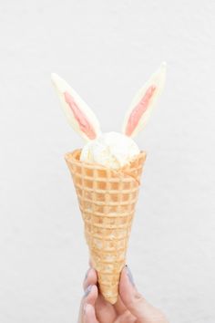 a hand holding an ice cream cone with bunny ears on it