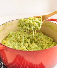 a wooden spoon scooping guacamole from a red pot