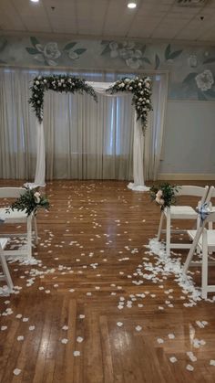 the ceremony room is decorated with white flowers and petals on the wooden floor, along with chairs