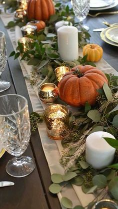 the table is set with candles, pumpkins and greenery for a festive look