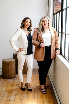 two women standing next to each other near a window