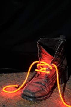 a pair of shoes with neon lights attached to them on a table in front of a black background