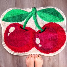 someone is standing on the floor in front of a rug with two cherries