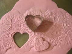 two heart shaped cookie cutters sitting on top of a pink paper plate with an ornate design