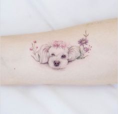 a small white dog with flowers on it's arm is shown from the side