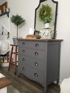 the dresser is painted gray and has gold knobs on it, along with a mirror