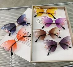 six pairs of colorful sunglasses in a box on top of a metal table with the words bride and bridal written on them