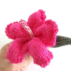 a hand holding a pink knitted flower