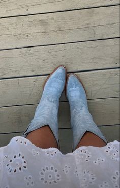 a woman's feet wearing blue shoes and white dress on a wooden floor with wood planks