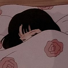 a woman laying in bed under a blanket with flowers on it and covering her face