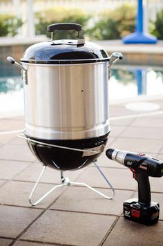 a large metal pot sitting on top of a table next to a small camera near a pool