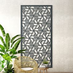 a rattan chair and potted plant in front of a decorative screen on the wall