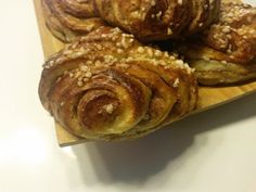 several pastries sitting on top of a wooden cutting board with sesame seeds around them