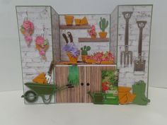 a miniature garden scene made out of paper with gardening tools and flowers in the background