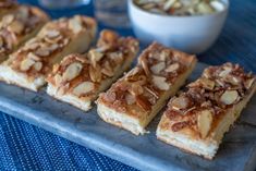 several pieces of dessert sitting on top of a blue tray next to a bowl of nuts