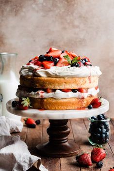 a cake with strawberries and whipped cream on top is sitting on a wooden table