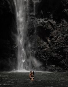 two people standing in front of a waterfall