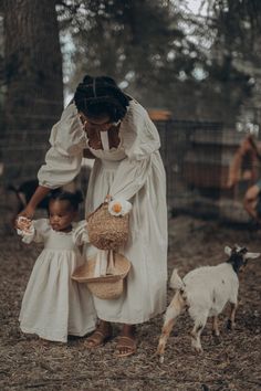 a woman in a white dress holding a basket next to a small goat