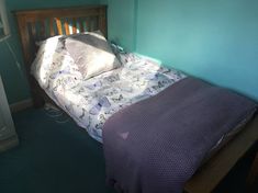 a bed sitting in the corner of a room with a purple blanket on top of it