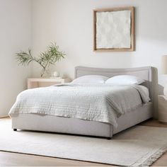 a bed with white sheets and pillows in a room next to a rug on the floor