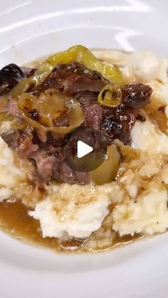 a white plate topped with mashed potatoes covered in gravy and meat toppings