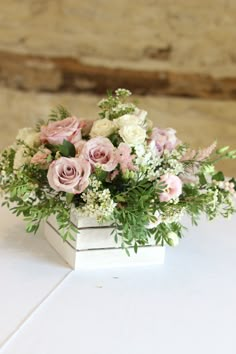 a bouquet of pink and white flowers in a square vase