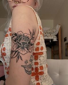 a woman with glasses and a flower tattoo on her arm