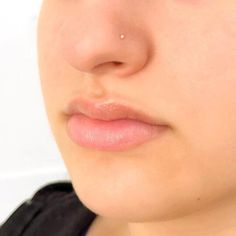 a close up of a woman's face with an ear piercing on her nose