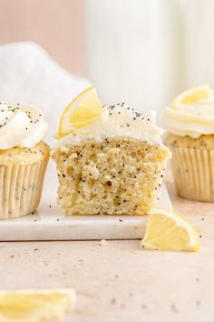 three cupcakes with lemon and poppy seed toppings on a white plate next to a glass of milk